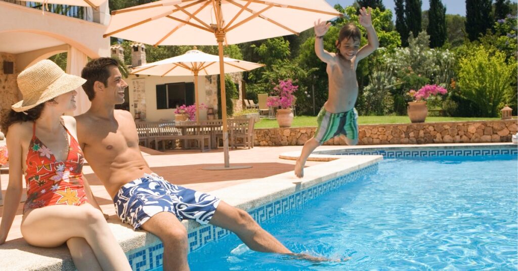 Family enjoying a clean, crystal clear swimming pool in Vermont South with a child jumping into the water.