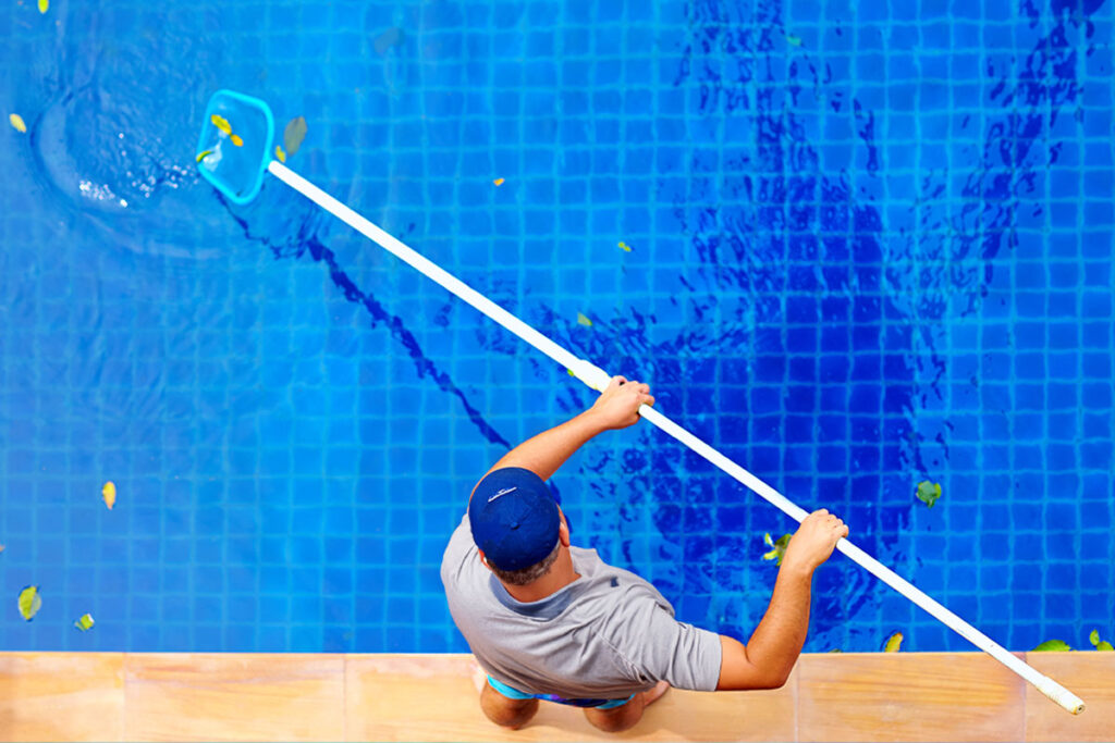 Pool Pro technician using a pool leaf skimmer net for regular swimming pool maintenance.